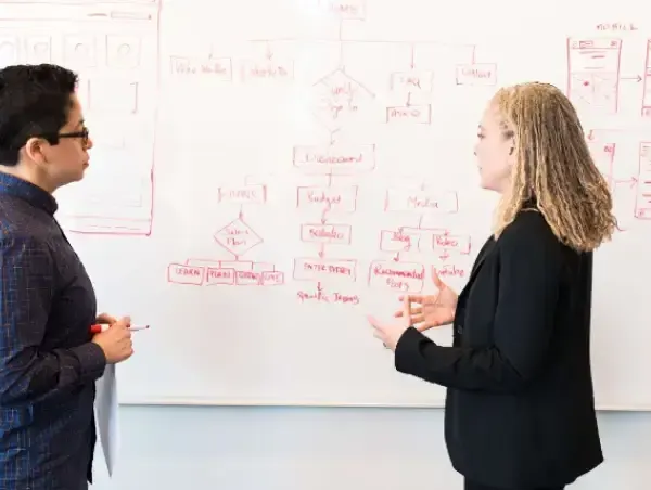 Deux personnes discutant d'optimisation UX sur un tableau blanc.