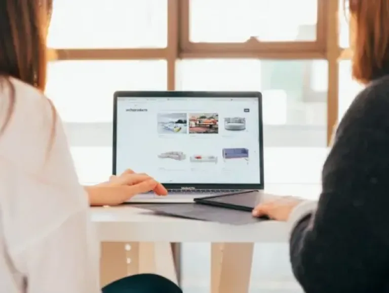 Image de deux femmes devant un site web sur ordinateur.